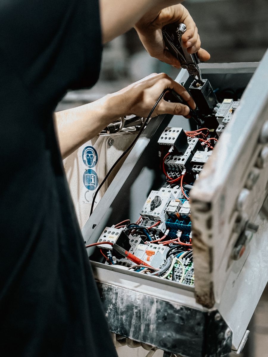 Elektriker verdrahtet Schütze und Klemmen in einem geöffneten Installationsverteiler.